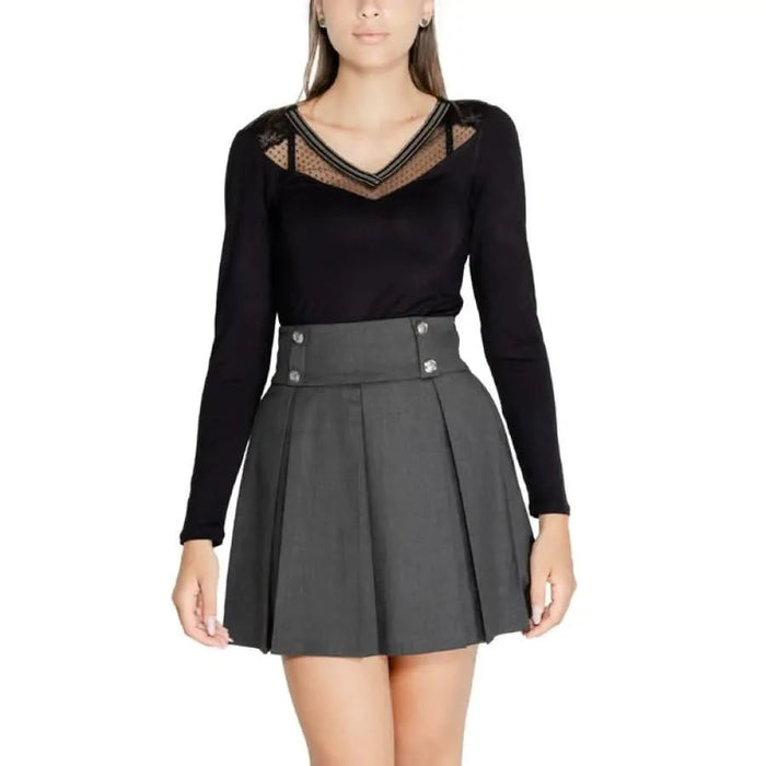 Woman in black long-sleeved top and gray pleated miniskirt from Morgan De Toi