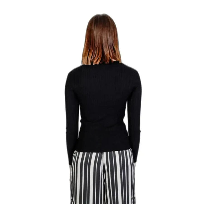 Woman in black sweater and striped pants from Only Women Knitwear, embodying urban city fashion