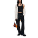 Woman in black tank top and pants with white Desigual cardigan and colorful handbag