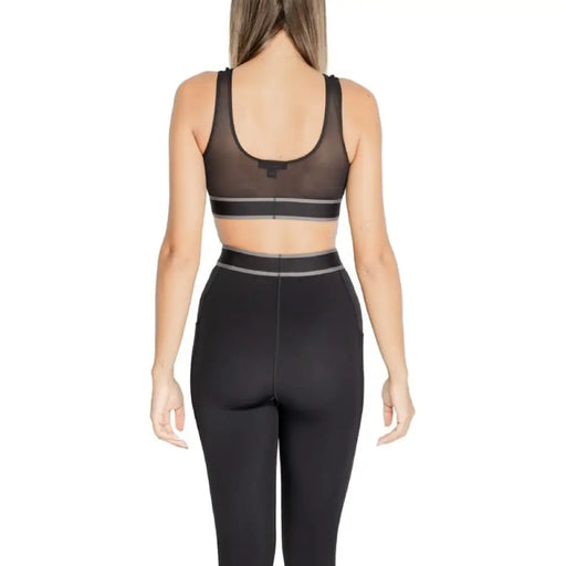 Woman in black workout leggings and matching sports bra from Calvin Klein Sport