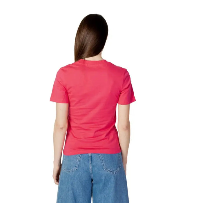 Woman in bright pink Calvin Klein T-shirt and blue jeans, viewed from behind