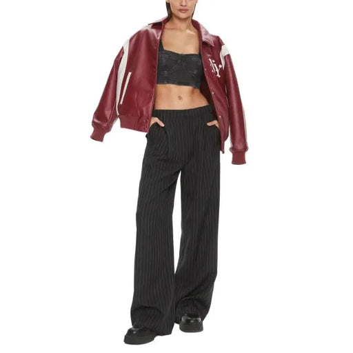 Woman in burgundy varsity jacket, black crop top, and wide-leg black pants