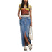 Woman in colorful crop top and long denim skirt with white sneakers and handbag