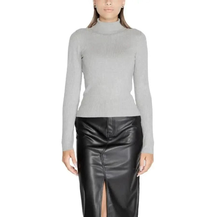 Woman in light gray turtleneck sweater and black leather skirt by Jacqueline De Yong