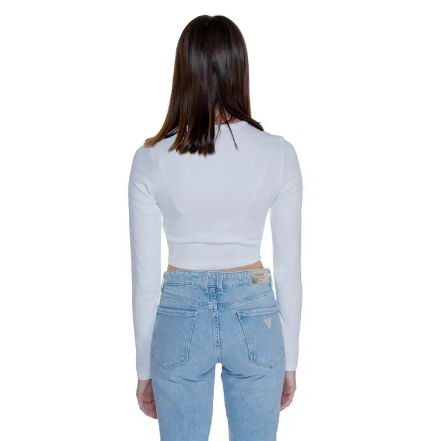 Woman in white Tommy Hilfiger crop top and light blue jeans, showing back view