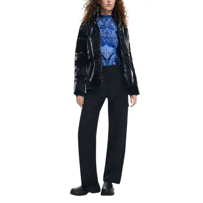 Woman in shiny black jacket, blue patterned top, and black trousers from Desigual