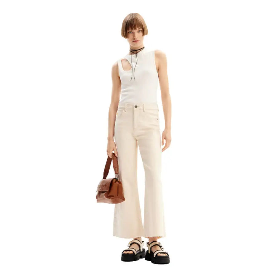 Stylish woman in white top, cream pants, platform sandals, and brown handbag