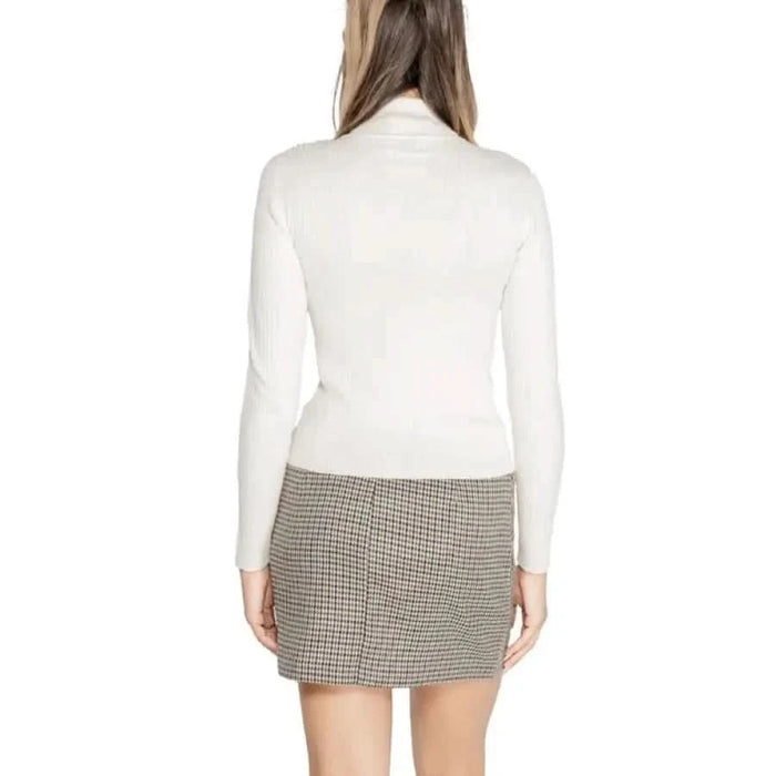 Woman in a white turtleneck sweater and plaid mini skirt from Jacqueline De Yong Knitwear