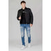 Young man in black puffer jacket, distressed jeans, and white sneakers by Antony Morato